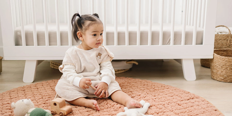 Toddler sitting on the floor with her toys wearing the Zinoa Sleepsuit